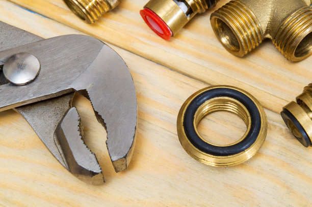 管道工扳手和木板上的黄铜配件特写。水管维修方案图片下载