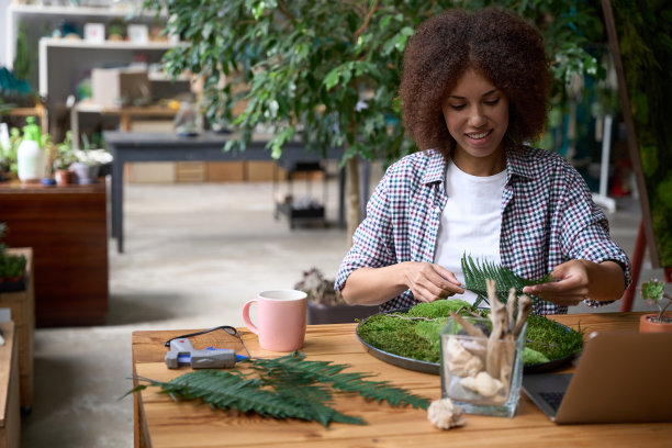 开朗的女人在花店办公室享受苔藓的工作图片下载