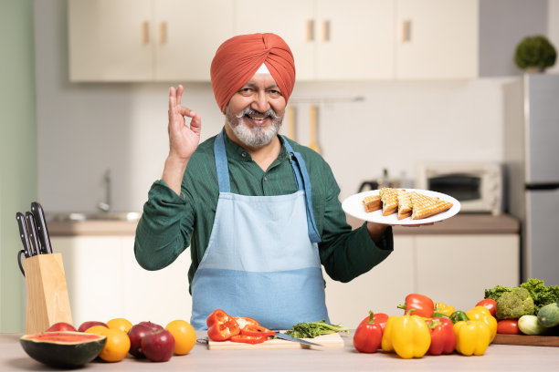 在厨房里戴头巾的成熟锡克教男子，库存照片图片下载