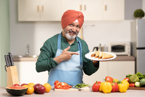 在厨房里戴头巾的成熟锡克教男子，库存照片图片下载