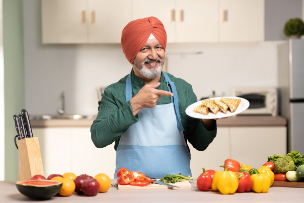 在厨房里戴头巾的成熟锡克教男子，库存照片图片下载