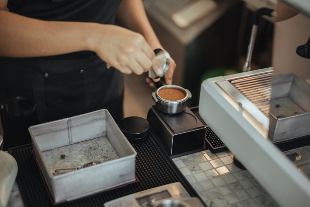 咖啡师用捣固器将咖啡粉压入移动过滤器。咖啡师用咖啡机制作咖啡的特写镜头。咖啡老板的概念。图片下载