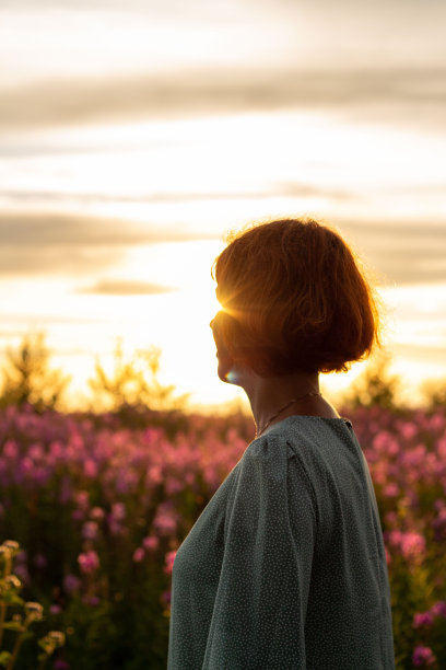 年轻美丽的女孩站在阳光下与鲜花图片下载