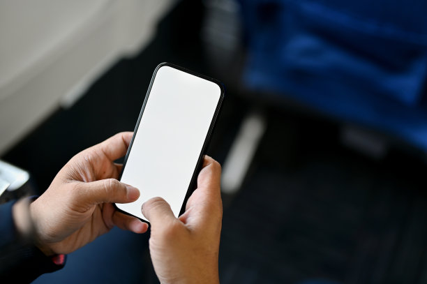 一名男性乘客在飞行途中使用智能手机。智能手机白屏模型图片下载