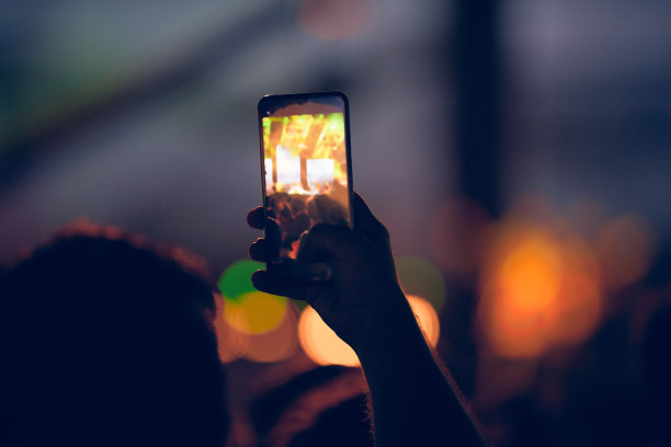 一个人拿着现代智能手机在音乐会。图片下载