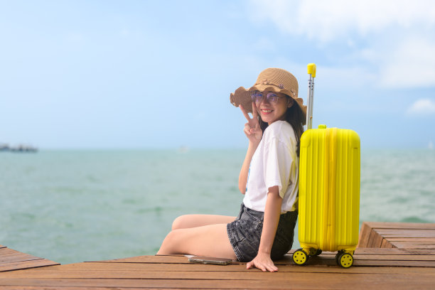 在酒店带行李箱的人，带黄色行李的快乐女旅行家，带大包小包的人，出国度假的快乐游客图片下载