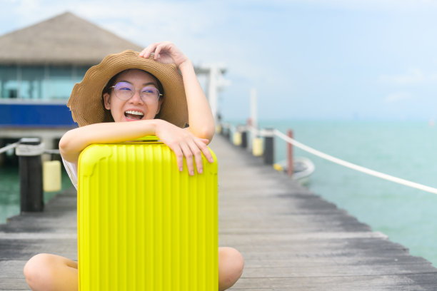 在酒店带行李箱的人，带黄色行李的快乐女旅行家，带大包小包的人，出国度假的快乐游客图片下载