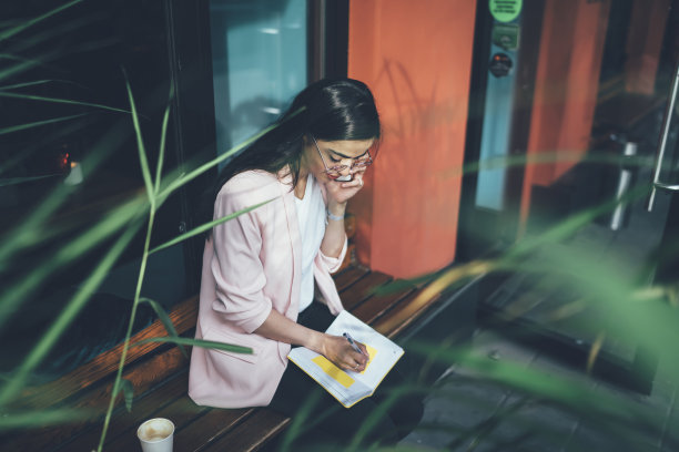 路边咖啡店的女经理打电话给送货服务，在城市环境下使用智能手机小工具讨论商品订单，格鲁吉亚妇女一边打电话一边计划组织图片下载