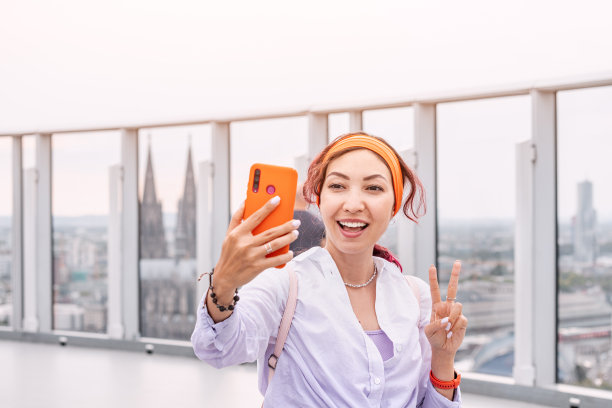 一名游客女孩在科隆摩天大楼顶部的观景台上自拍，背景是大教堂图片下载