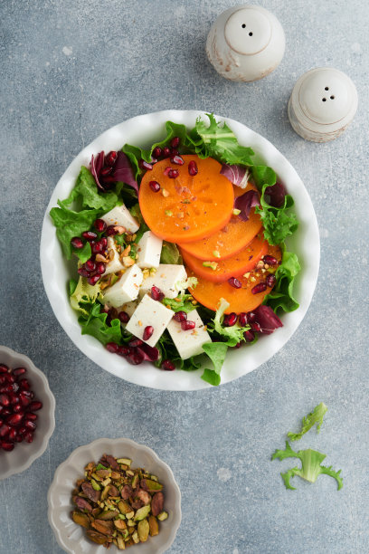 沙拉。新鲜蔬菜沙拉配羊乳酪，柿子，石榴和开心果，白盘子。健康美味的冬季圣诞沙拉。健康均衡的饮食。前视图。图片下载
