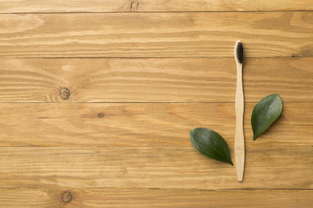 牙刷与绿色树叶木制背景。俯视图图片下载