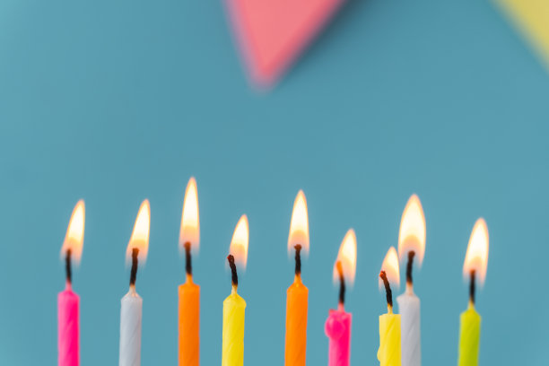 蓝色背景上的白色奶油奶酪多色蜡烛生日蛋糕图片下载
