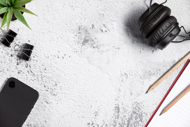 平面布局表的俯视图组成与智能手机，钢笔，记事本和耳机在白灰色背景图片下载