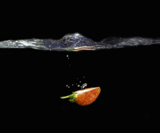 新鲜草莓(一半)放入水中飞溅图片下载