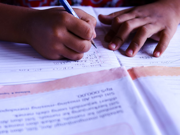 男同学在桌子上的一本书上写字。有选择性的重点。图片下载