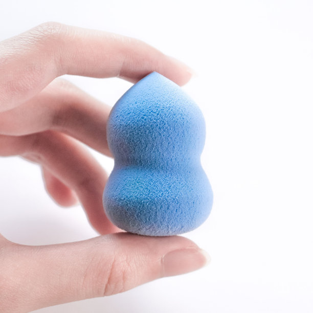 特写镜头，一只手拿着一个蓝色的美容海绵图片下载