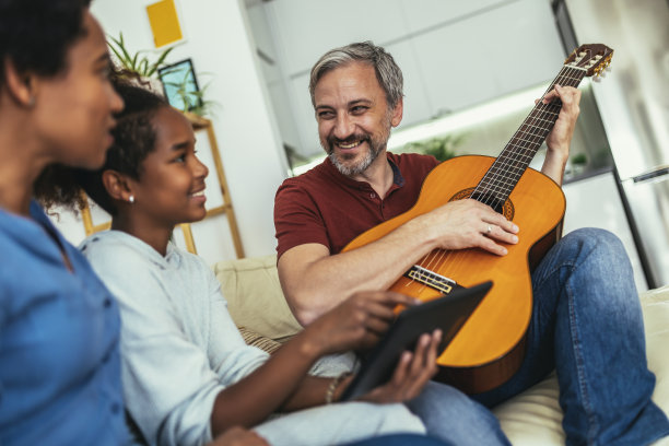 一个男人为他的女儿和妻子唱歌和弹吉他。图片下载