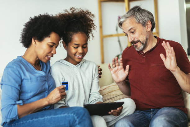 家庭使用数码平板电脑和信用卡在家里进行网上购物。图片下载