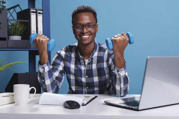 公司运动商人在办公室坐在办公桌前举重。图片下载