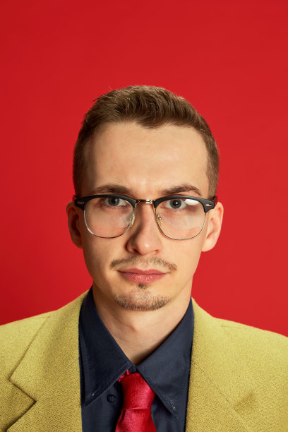 年轻男子的肖像在时尚的夹克和眼镜摆造型的红色背景。认真专注的脸。团队的领导者。商业、情感、职业的概念图片下载