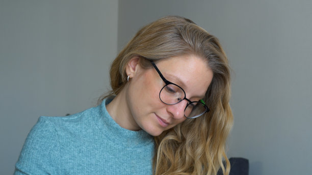 戴着眼镜、面带微笑的女学生坐在桌前，拿着笔记本电脑和咖啡，写着小说和短篇小说。女人会思考和构思她书中的情节。很多想法和灵感。图片下载