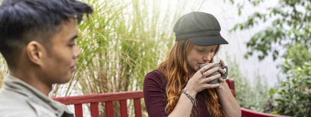 水平横幅或标题沉思年轻红发女子喝拿铁或美国咖啡与多元文化的朋友在酒吧花园图片下载