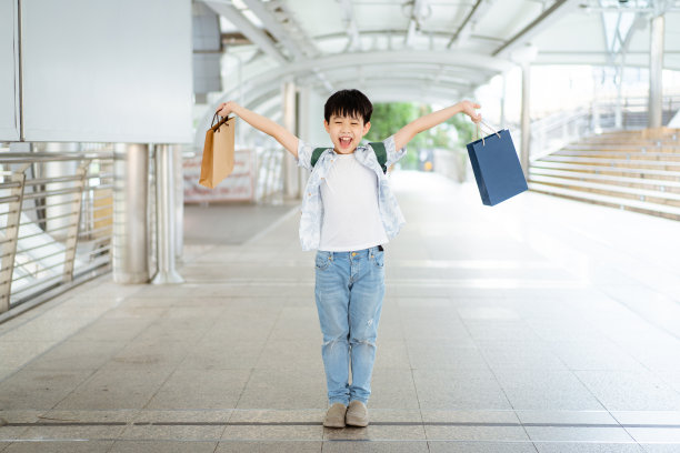 快乐的男孩拿着一个购物袋。图片下载