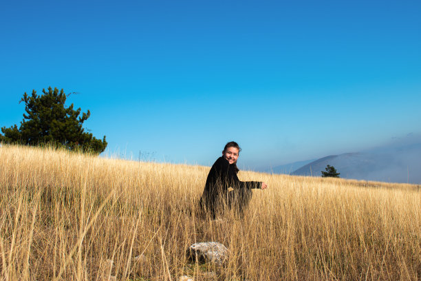 女孩在阳光多雾的一天在山顶上冷却-库存照片图片下载
