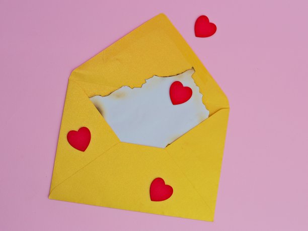 黄色信封，里面装着旧纸，粉红色背景上贴着心形贴纸图片下载