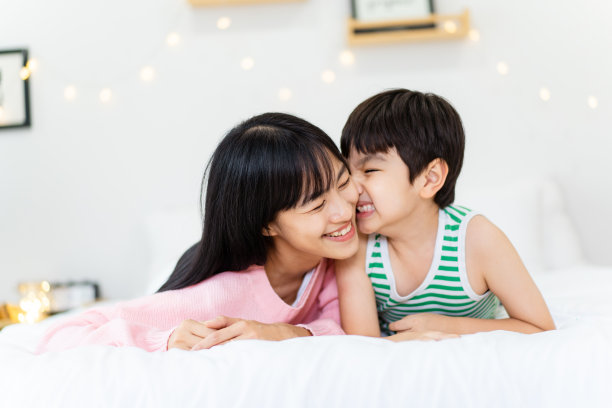 母亲和儿子一起在床上玩耍。图片下载