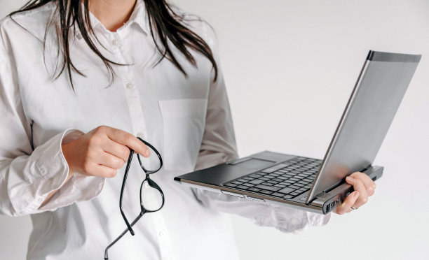 一个女人拿着眼镜和笔记本电脑的特写图片下载