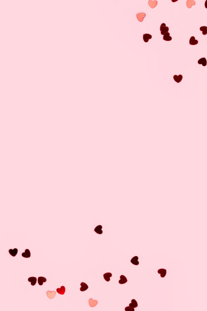 粉色背景上心形的红色纸屑。图片下载