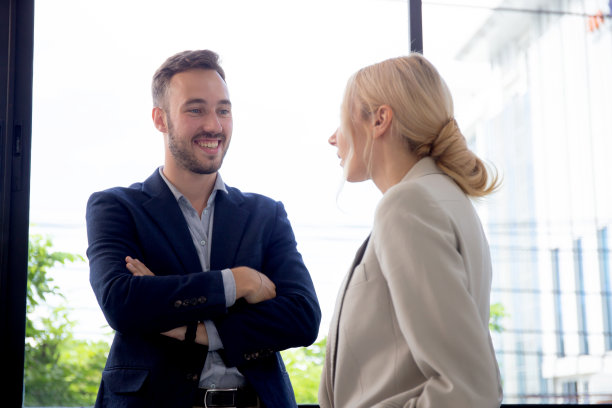 年轻的白人商人在办公室休息时与合作伙伴或女商人站在一起交谈，商业男子与合作伙伴女在工作场所一起放松，两人。图片下载