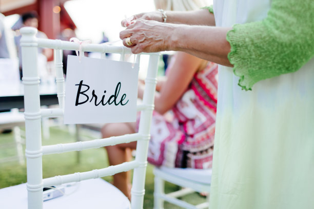 在酒店餐厅举行的婚礼上，一张白纸挂在椅子上，等待着庆祝。有许多客人参加了这次活动。图片下载