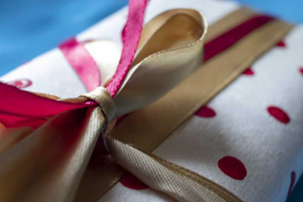 彩色礼盒。红色缎面蝴蝶结礼物。一个真正的盒子，用红丝带系着，站在前面的地面上图片下载