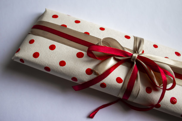 彩色礼盒。红色缎面蝴蝶结礼物。一个真正的盒子，用红丝带系着，站在前面的地面上图片下载