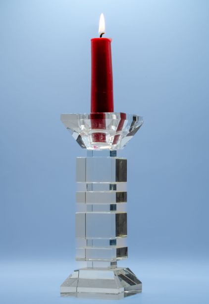 蓝色背景下的透明玻璃烛台上的红色蜡烛特写图片下载