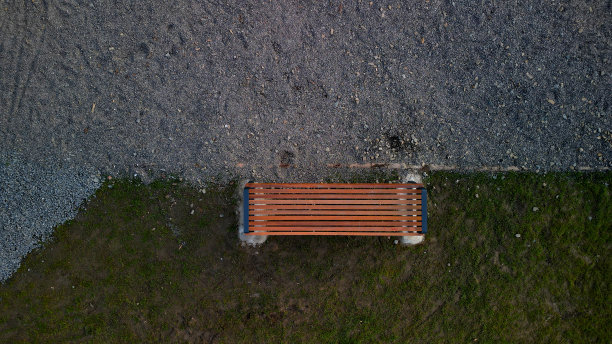 红色的木长凳下面的镶板上是一个矩形的混凝土抗刮米黄色路径，游客的鞋子开花浪漫的花圃和草坪，高角度观看，上图图片下载