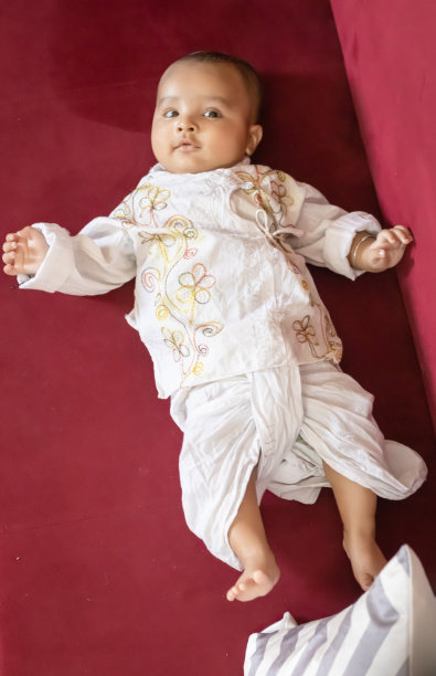 婴儿男孩在传统的印度服装躺在沙发上可爱的面部表情在室内图片下载