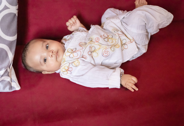 婴儿男孩在传统的印度服装躺在沙发上可爱的面部表情在室内图片下载