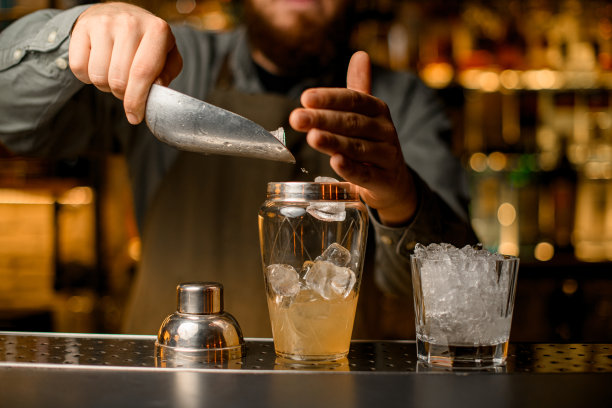 酒保用勺子倒冰块的摇酒器的正面视图图片下载