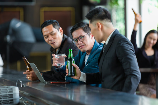 亚洲商人或合伙人拿着一瓶瓶啤酒，在办公室工作空间里讨论项目工作图片下载