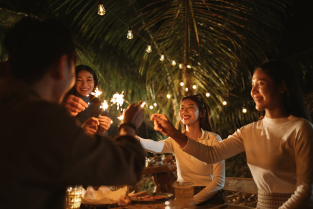 快乐的亚洲朋友们在节日庆祝活动中，在户外晚会上玩烟火。图片下载