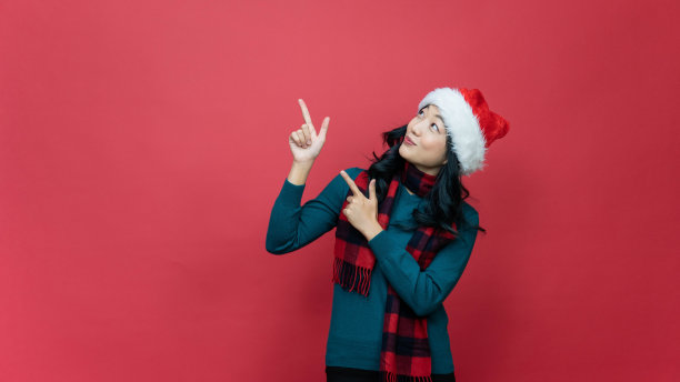 肖像照片正面女士在圣诞老人的帽子点食指，广告空间直接方式x-mas圣诞新年广告推广穿着风格时尚毛衣孤立在红色背景图片下载