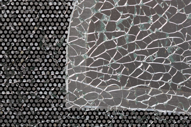 带穿孔箔的破碎玻璃窗格。图片下载