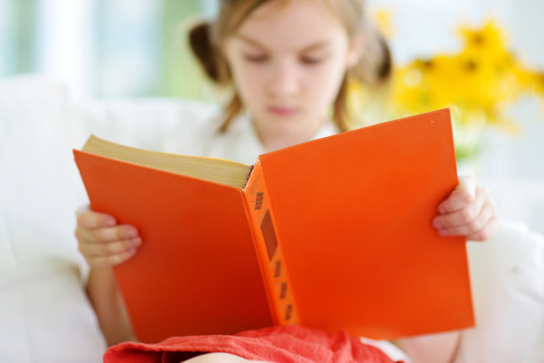 可爱的小女孩在白色的客厅看书图片下载