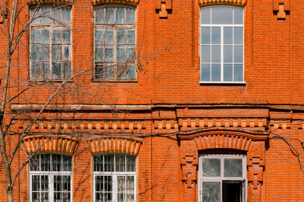 古老的立面由红砖制成，白色圆形的复古窗户。时尚。体系结构。历史。遗产。首页枯燥乏味的城市。工业风格。红砖墙图片下载