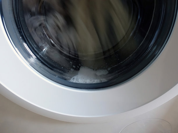 装有肥皂的前置洗衣机，洗衣衣物在里面旋转图片下载