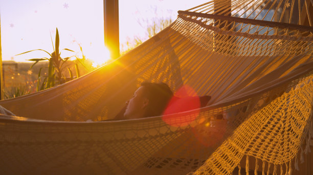 特写:年轻女子盖着温暖的毯子在舒适的吊床上打盹图片下载