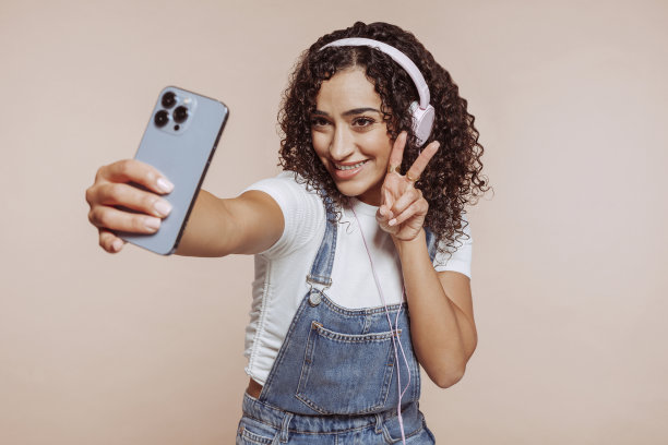 快乐的女人一边自拍一边戴着耳机听音乐图片下载